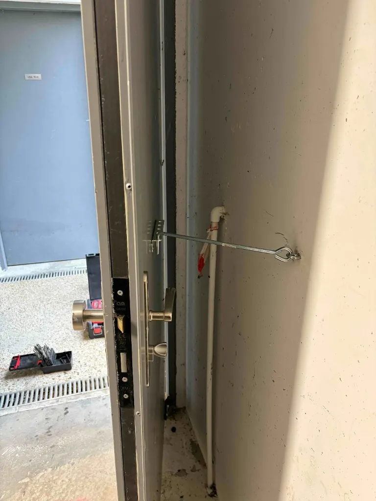 Installation et réglage d’un ferme-porte avec barre de maintien sur porte de local vélos
