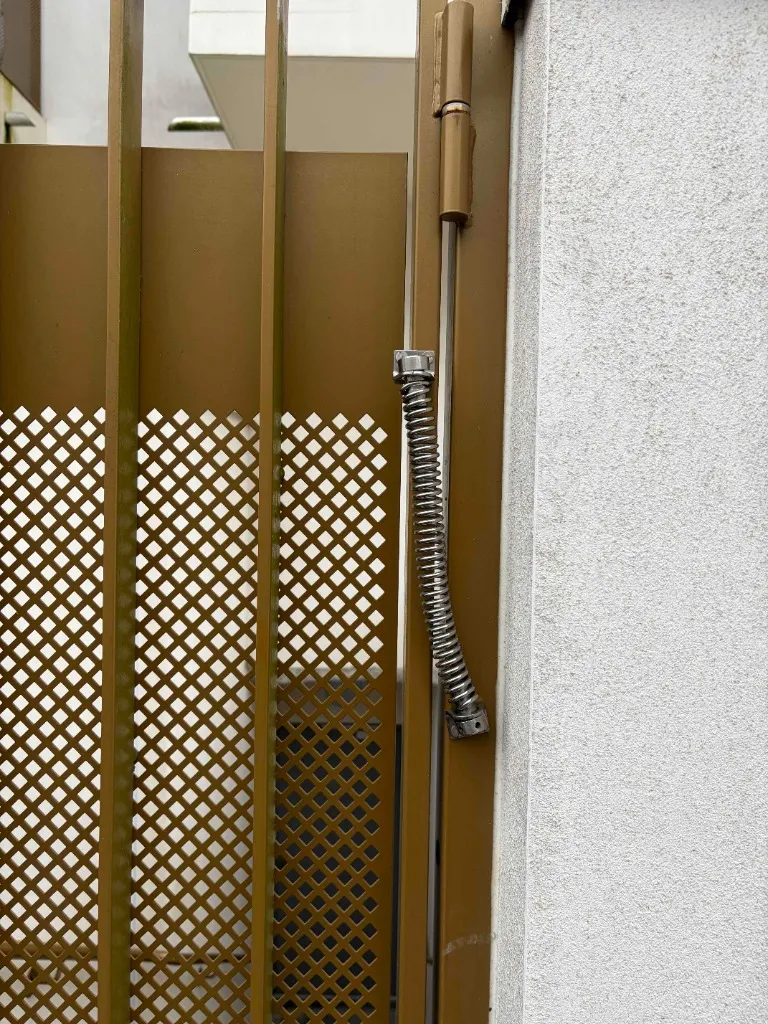 Ferme-porte à ressort installé sur un portail métallique de résidence